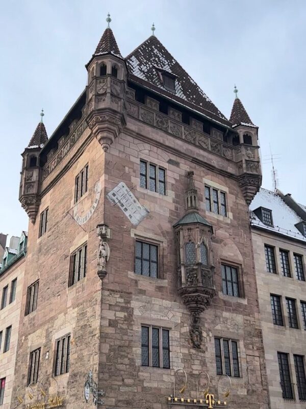 The sandstone Nassauer house with its four turrets on each corner, standing opposite the Lorenzkirche, crowds mills about beneath it.