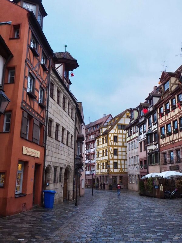 An elegant street is shown filled with half timbered houses and cobblestones