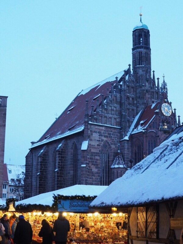 Christmas market stalls glow in the winter gloom in front of the Frauenkirche and answer is Nuremberg worth visiting