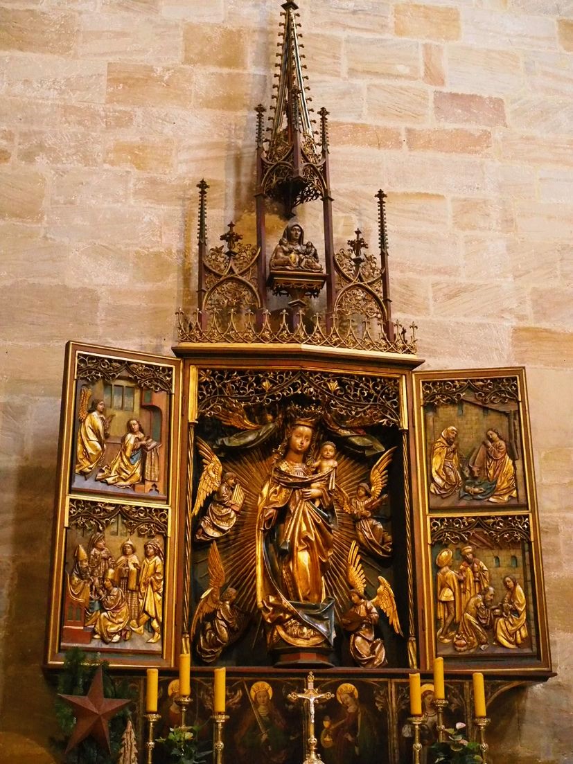 Gold tones beam out from a highly intricate and lavishly decorated altar, the main panel displays a figure of the Virgin Mary and infant Jesus, held as a masterpiece of sculpture within the Bamberg Cathedral. Discover more sights on this walking tour & map of Bamberg, Germany