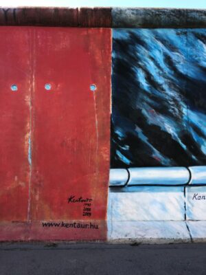 A dark red panel with painted rivet holes and rivets adjoins a mural painted with a dark background and platinum railing, small black signatures appear in the bottom corner of the relevant artists.