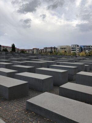 Large, uneven, dark grey blocks stretch off into the distance, bounded by city buildings under a cloudy sky.