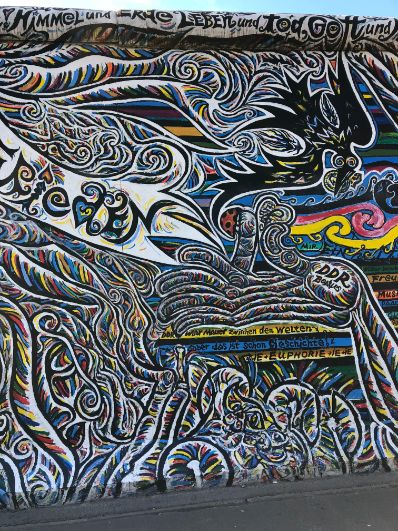 Multicoloured, swirling patterns make up a intruiging panel of the East Side Gallery, with motifs of a hand and writing interspersed with the illustrations.