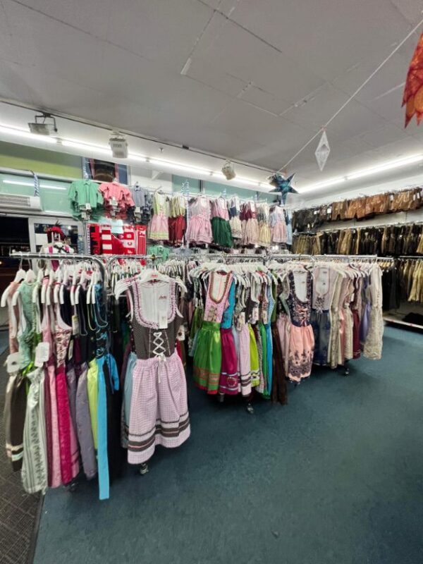 A store is shown filled with different dirndls and lederhosen, Bavarian traditional dress, in all colours of the rainbow.