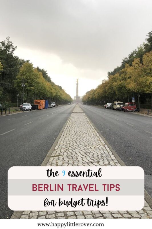 A long avenue is shown lined with trees in varied shades of green and a few parked vehicles. At the far end is a large column, backlit by the setting sun. The text read the 9 essential Berlin travel tips for budget trips.